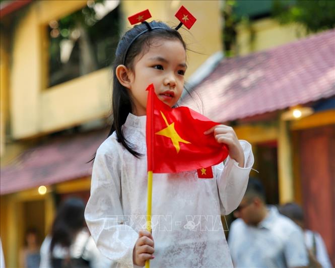 Các em nhỏ được bố mẹ chụp ảnh cùng Quốc kỳ. Ảnh: Tuấn Đức - TTXVN