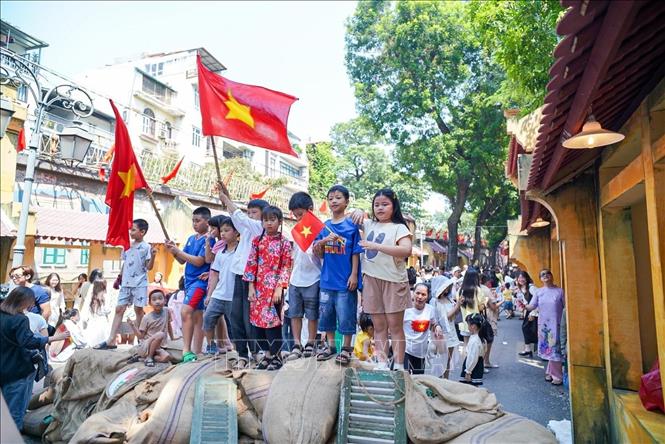 Các em nhỏ với Quốc kỳ trên phố bích họa Phùng Hưng. Ảnh: Khánh Hòa - TTXVN