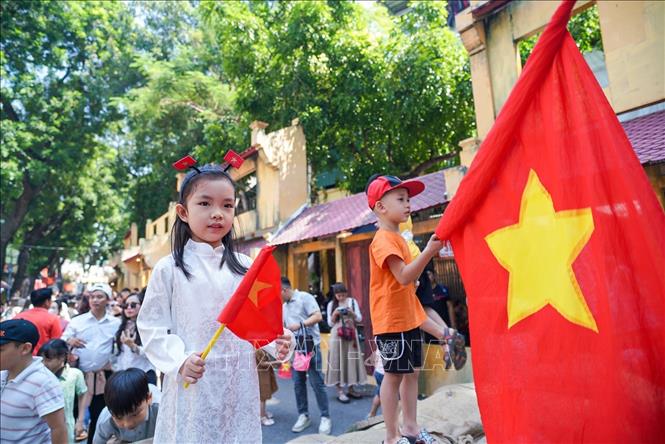 Các em nhỏ chụp ảnh cùng Quốc kỳ tại phố Phùng Hưng. Ảnh: Khánh Hòa - TTXVN