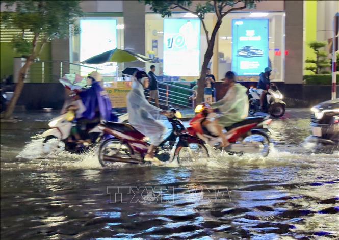 Người dân thành phố Long Xuyên, An Giang vất vả di chuyển qua các tuyến đường ngập sâu trong nước. Ảnh: Thanh Sang-TTXVN