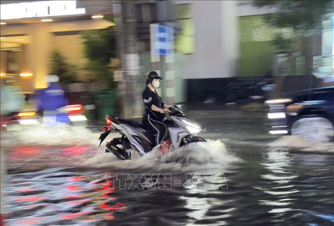 Người dân thành phố Long Xuyên, An Giang vất vả di chuyển qua các tuyến đường ngập sâu trong nước. Ảnh: Thanh Sang-TTXVN