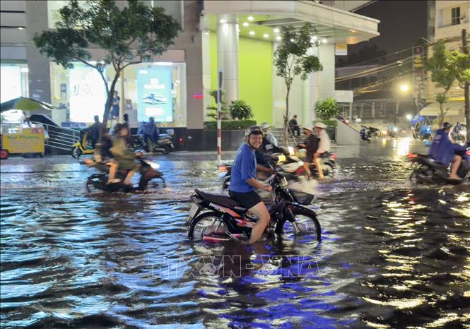 Người dân thành phố Long Xuyên, An Giang vất vả di chuyển qua các tuyến đường ngập sâu trong nước. Ảnh: Thanh Sang-TTXVN