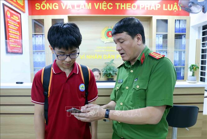 Trung tá Nguyễn Anh Tuấn hướng dẫn công dân cài đặt ứng dụng VNeID trên điện thoại di động. Ảnh: Phạm Kiên - TTXVN
