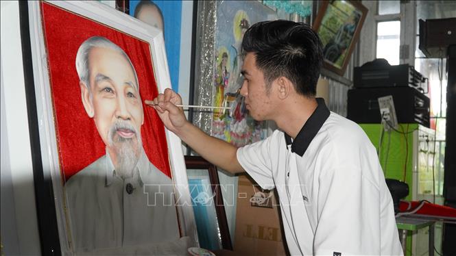 Anh Nguyễn Minh Trí hoàn thiện bức tranh gói vải chân dung Chủ tịch Hồ Chí Minh. Ảnh: Văn Sĩ - TTXVN                                     