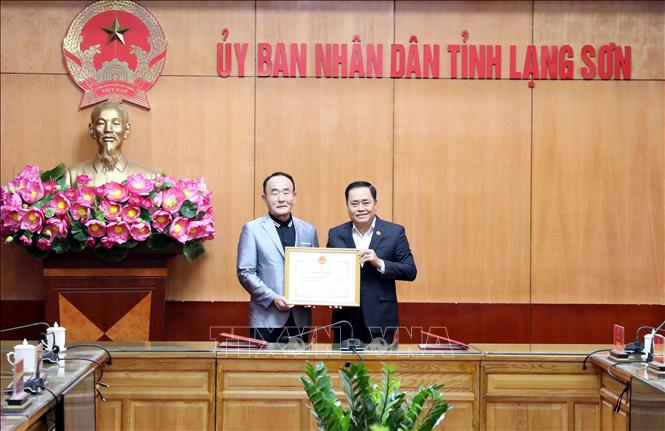 Chủ tịch UBND tỉnh Lạng Sơn Hồ Tiến Thiệu (phải) trao Bằng khen cho ông Yun Eun Ho, Chủ tịch Tổ chức DIVA vì những đóng góp trong công tác phát triển kinh tế - xã hội địa phương. Ảnh: Văn Đạt - TTXVN
