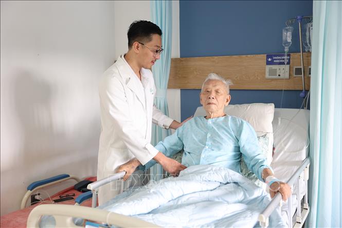 Bác sỹ Khoa Tim mạch can thiệp, Bệnh viện Đại học Y Dược Buôn Ma Thuột (thành phố Buôn Ma Thuột, tỉnh Đắk Lắk) thăm khám cho bệnh nhân Lê Văn Q (90 tuổi) sau ca phẫu thuật đặt stent graft đối với bệnh phình động mạch chủ bụng. Ảnh: TTXVN phát