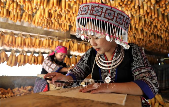 Du khách trải nghiệm vẽ tranh bằng sáp ong tại Nhà ngô Màng Mủ. Ảnh: Tuấn Anh – TTXVN 