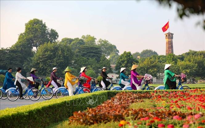 Phụ nữ Thủ đô đạp xe trên đường Điện Biên Phủ, ngang qua Cột cờ Hà Nội trong chương trình “Áo dài kết nối du lịch và di sản Hà Nội lần thứ nhất - năm 2023”. Ảnh: Tuấn Đức - TTXVN
