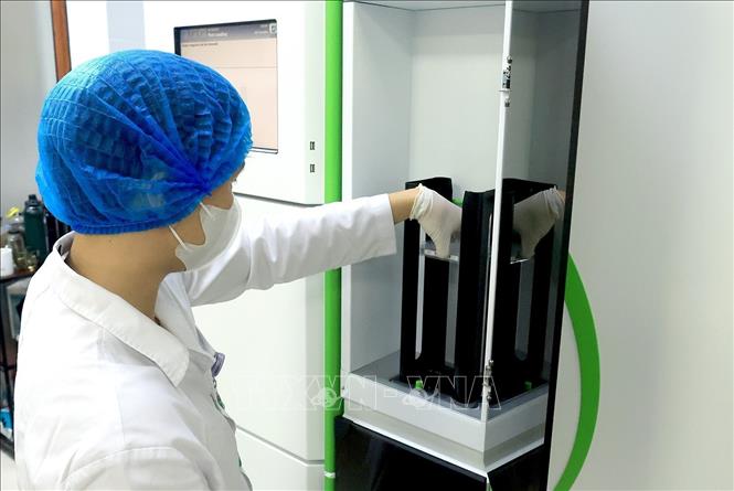 Đặt mẫu sàng lọc vào hệ thống máy kiểm tra tự động. Ảnh: Tuấn Anh - TTXVN