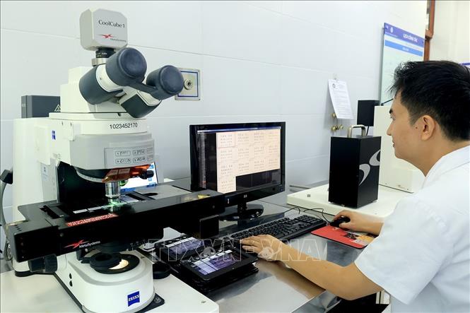Phân tích sơ đồ nhiễm sắc thể bằng hệ thống kính hiển vi huỳnh quang tự động. Ảnh: Tuấn Anh - TTXVN