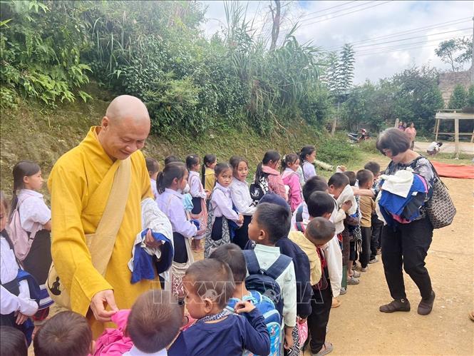 Thượng tọa Thích Minh Quang, Trưởng ban Điều phối và hợp tác Giáo hội Phật giáo Việt Nam tại Lào phát quần áo cho những trẻ em bị ảnh hưởng do lũ lụt ở Lào. Ảnh: TTXVN phát