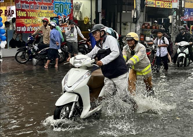 Các chiến sỹ CSGT lội nước, dầm mưa, vừa điều tiết giao thông, vừa giúp người dân vượt qua vùng trũng, ngập úng sâu ở đoạn Quốc lộ 50 - Nguyễn Văn Linh, Quận 8. Ảnh: Thanh Vũ-TTXVN