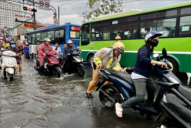 CSGT lội nước, dầm mưa, vừa điều tiết giao thông, vừa giúp người dân vượt qua vùng trũng, ngập úng sâu ở đoạn Quốc lộ 50 - Nguyễn Văn Linh, Quận 8. Ảnh: Thanh Vũ-TTXVN