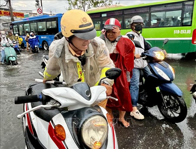 CSGT giúp người dân vượt qua vùng trũng, ngập úng sâu ở đoạn Quốc lộ 50 - Nguyễn Văn Linh, Quận 8. Ảnh: Thanh Vũ-TTXVN