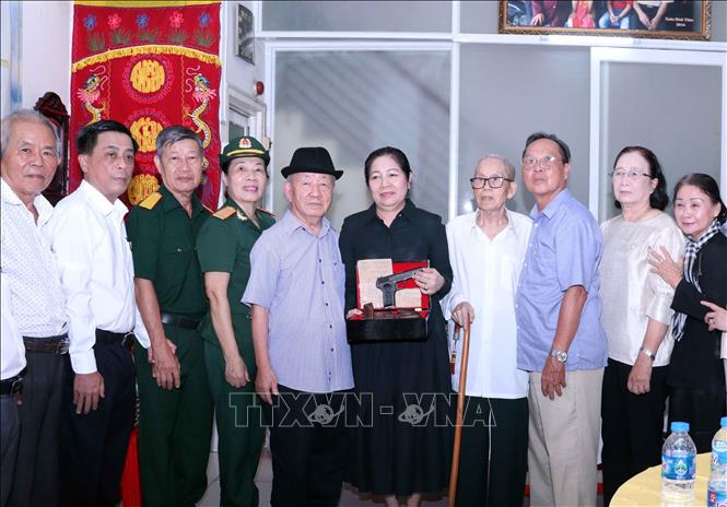 Đại diện các đơn vị và thân nhân bà Nguyễn Thị Mai chụp ảnh lưu niệm cùng hiện vật lịch sử của người nữ chiến sỹ biệt động Nguyễn Thị Mai. Ảnh: Xuân Khu-TTXVN