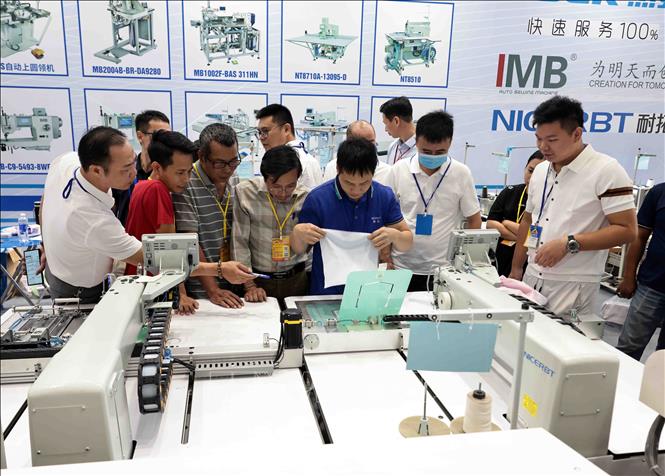 Khách tham quan gian trưng bày máy may, dán tự động. Ảnh: Trần Việt - TTXVN