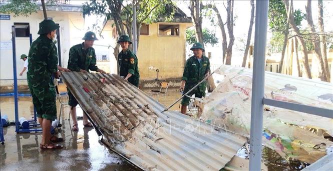 Các cán bộ, chiến sỹ hỗ trợ đơn vị trường học tại huyện Lệ Thủy dọn dẹp vệ sinh sau mưa, lũ. Ảnh: TTXVN phát