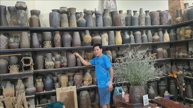 Anh Nguyễn Giang Anh, thị trấn Hương Canh, huyện Bình Xuyên giới thiệu về sản phẩm gốm Hương Canh của gia đình sản xuất. Ảnh: Nguyễn Trọng Lịch - TTXVN