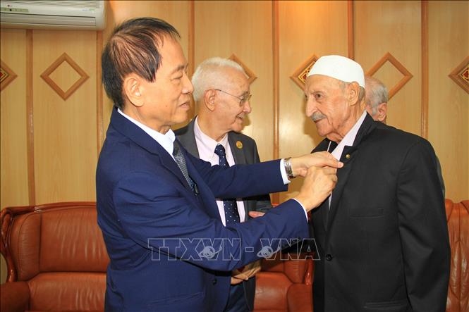 Các cựu chiến binh Algeria xúc động khi được ông Võ Hồng Nam, con trai Đại tướng Võ Nguyên Giáp, tặng huy hiệu có chân dung và chữ ký của Đại tướng. Ảnh: Trung Khánh - pv TTXVN tại Algeria 