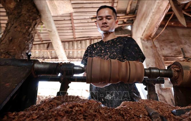 An artisan shapes the outside of a wood log. VNA Photo: Trần Việt