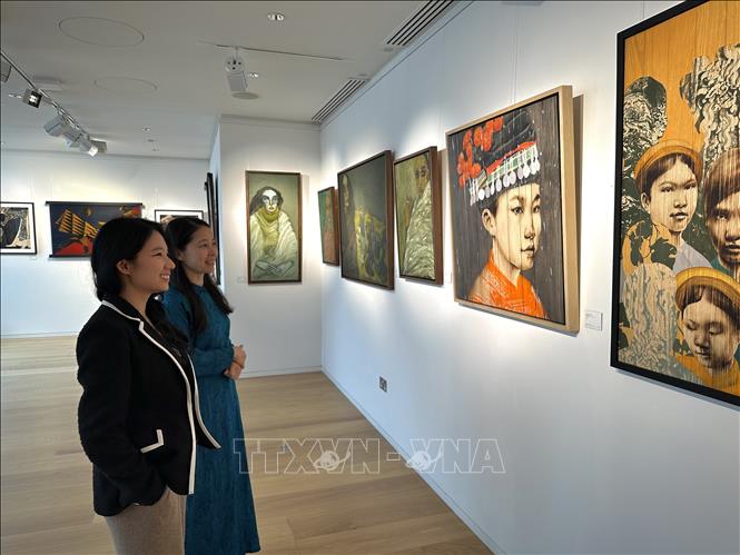 Nhân viên phòng tranh Thăng Long Art Gallery giới thiệu về các tác phẩm với khách tham quan. Ảnh: TTXVN phát