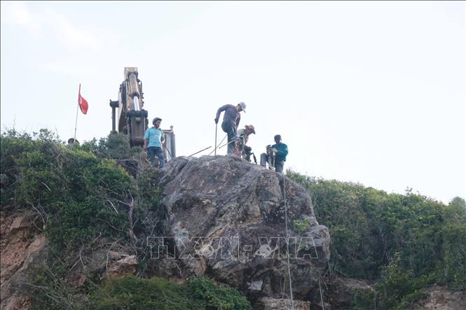 Lực lượng chức năng tiến hành khoan khối đá nằm trên đỉnh đèo Cù Hin. Ảnh: Đặng Tuấn -TTXVN
