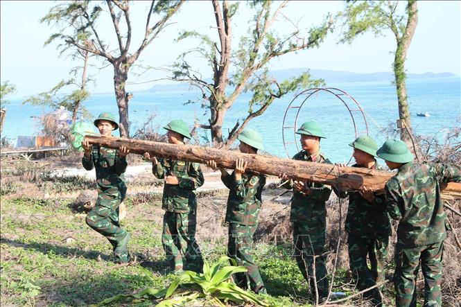 Bộ đội tiểu đoàn Đảo Cô Tô chặt, tỉa dọn dẹp cây gãy đổ giúp giao thông thuận lợi tại các điểm du lịch ở xã Đồng Tiến. Ảnh: Trọng Đức - TTXVN