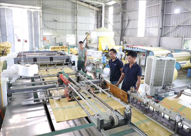 Công nhân Công ty Trách nhiệm hữu hạn Sản xuất bao bì Trường Thịnh điều hành máy móc trong quá trình sản xuất. Ảnh: Đức Phương - TTXVN