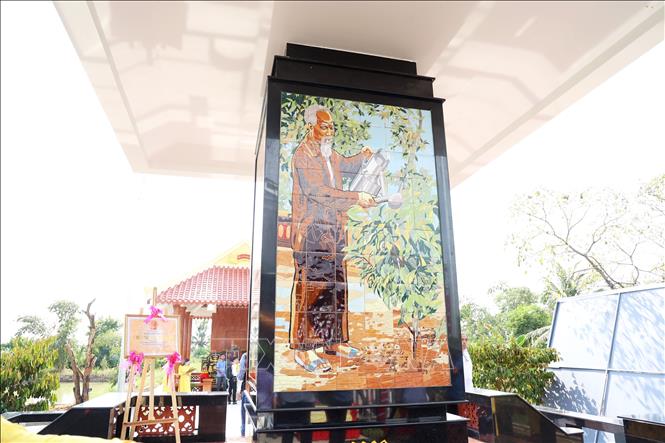 Hình ảnh Bác Hồ tưới cây vú sữa miền Nam trên Bia kỷ niệm Bác Hồ với cây vú sữa miền Nam. Ảnh: Hồng Đạt - TTXVN