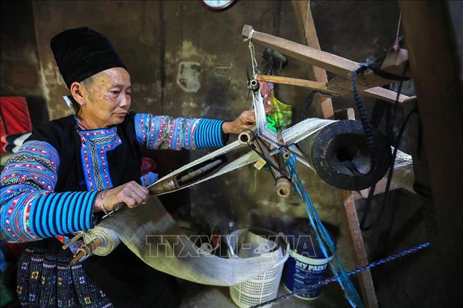 Một người phụ nữ Mông ở xã Pà Cò miệt mài bên khung cửu để dệt ra những tấm vải thổ cẩm Mông bền đẹp. Ảnh: Trọng Đạt-TTXVN