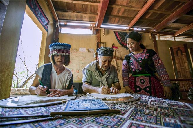 Du khách Pháp trải nghiệm vẽ sáp ong trên vải thổ cẩm người Mông tại Homestay Y Múa xã hang Kia. Ảnh: Trọng Đạt-TTXVN