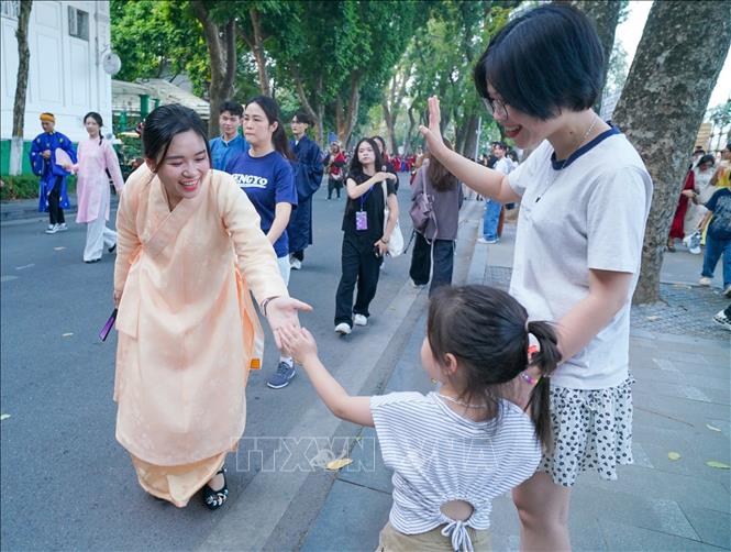 Du khách giao lưu với người diễu hành. Ảnh: TTXVN