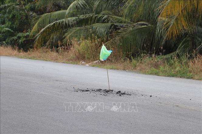 Người dân dùng vật liệu thô sơ cắm tạm báo hiệu những nơi nguy hiểm trên đường Lê Quang Công (Tiền Giang). Ảnh: Minh Trí - TTXVN