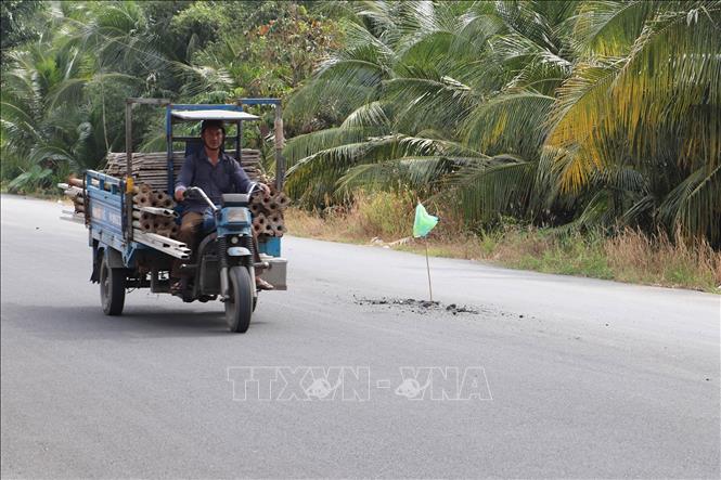 Người dân dùng vật liệu thô sơ cắm tạm báo hiệu những nơi nguy hiểm trên đường Lê Quang Công (Tiền Giang). Ảnh: Minh Trí - TTXVN