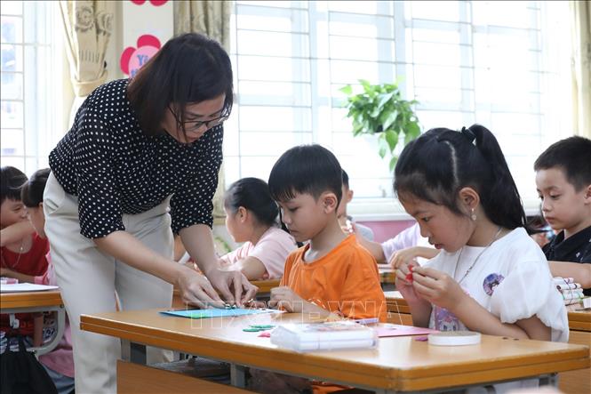 Hướng dẫn học sinh lớp 4A4, trường Tiểu học thị trấn Cao Lộc (Lạng Sơn) làm bưu thiếp chúc mừng 20/10. Ảnh: Anh Tuấn - TTXVN