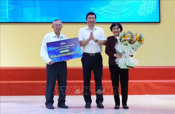 Lãnh đạo Công ty Cổ phần Dược phẩm Imexpharm (bìa phải) trao bảng tượng trưng kinh phí tài trợ khen thưởng học sinh, sinh viên, vận động viên và giáo viên, huấn luyện viên đạt thành tích xuất sắc. Ảnh: Nhựt An - TTXVN