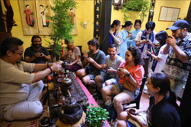 Các du khách nước ngoài thưởng thức trà tại Ngôi nhà di sản. Ảnh: Minh Đức – TTXVN