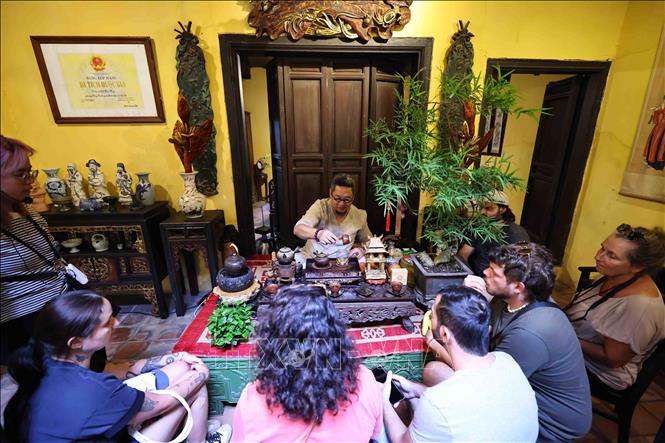 Nghệ nhân trà Nguyễn Cao Sơn thực hành và giải thích với các du khách nước ngoài từng động tác pha trà truyền thống, từ đun nước, tráng ấm, tới hãm trà sao cho vừa độ. Ảnh: Minh Đức – TTXVN