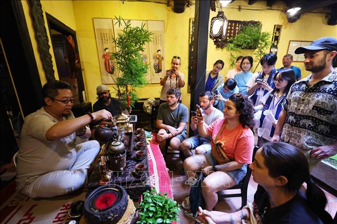Nghệ nhân trà Nguyễn Cao Sơn thực hành và giải thích với các du khách nước ngoài từng động tác pha trà truyền thống, từ đun nước, tráng ấm, tới hãm trà sao cho vừa độ. Ảnh: Minh Đức – TTXVN