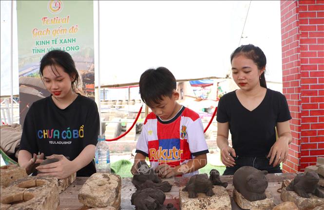 Các bạn trẻ tham gia hoạt động trải nghiệm sản xuất quà tặng gốm đỏ Vĩnh Long. Ảnh: Lê Thúy Hằng - TTXVN