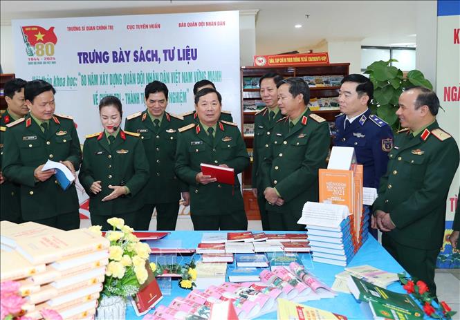 Thượng tướng, Tiến sĩ Lê Huy Vịnh, Thứ trưởng Bộ Quốc phòng và các đại biểu tham quan gian trưng bày tài liệu, sách về thành tựu 80 năm QĐND Việt Nam. Ảnh: Trọng Đức - TTXVN