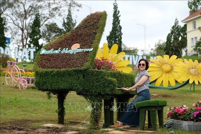 Một du khách tạo dáng chụp hình với đàn piano bằng cây xanh tại công viên hoa đường Trần Quốc Toản. Ảnh: Nguyễn Dũng – TTXVN 
