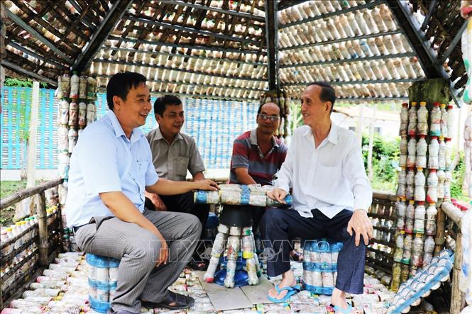 Khu du lịch sử dụng các vỏ chai nhựa, bao nilon tái chế làm tường cho nhà, phòng nghỉ, quán cà phê, hàng rào của cựu chiến binh Đoàn Công Khanh (bên phải) ở xã Sông Thuận, huyện Châu Thành (tỉnh Tiền Giang) đã thu hút hàng trăm khách du lịch đến tham quan mỗi ngày. Ảnh: Hữu Chí – TTXVN