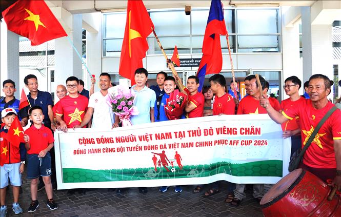 Các cổ động viên Việt Nam tại Lào và cộng đồng người Việt Nam tại Lào chụp ảnh kỷ niệm với HLV Kim Sang-sik và một số cầu thủ đội tuyển quốc gia Việt Nam bên ngoài sảnh đến tại sân bay quốc tế Wattay. Ảnh: Xuân Tú - PV TTXVN tại Lào