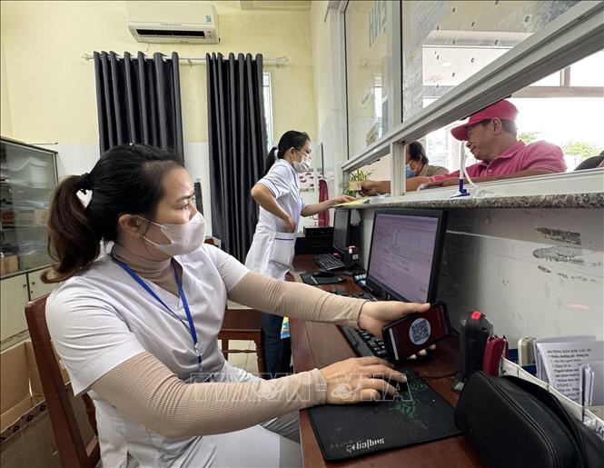 Nhân viên y tế quét mã lấy số và đăng ký khám bệnh tại các ki ốt phát số tự động. Ảnh: Đinh Hương - TTXVN