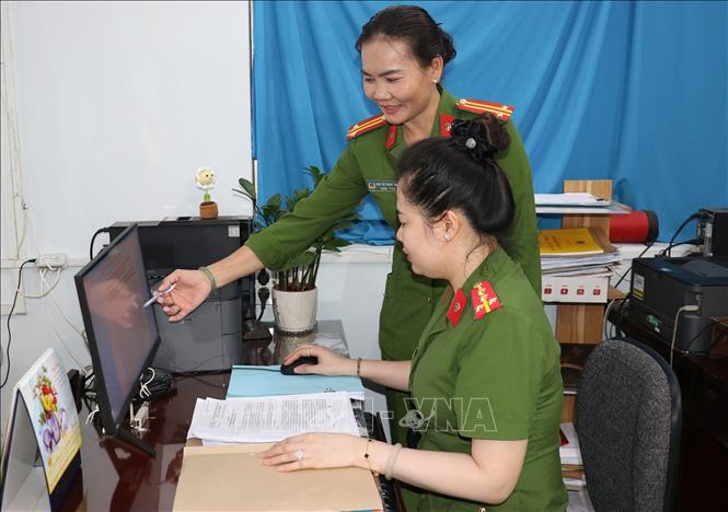 Trung tá Đinh Thị Thoa (đứng) trao đổi nghiệp vụ cùng đồng nghiệp trong đơn vị. Ảnh: Hữu Chí - TTXVN