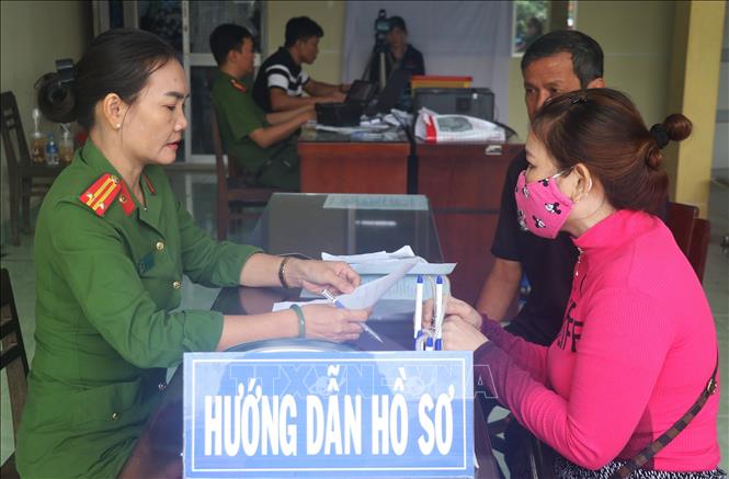 Trung tá Đinh Thị Thoa hỗ trợ người dân đến làm thủ tục cấp thẻ căn cước công dân. Ảnh: Hữu Chí - TTXVN