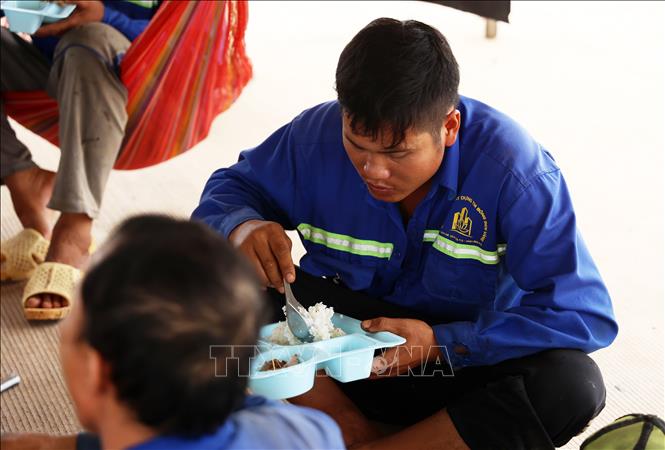 Công nhân ăn cơm trưa ngay trên công trường thi công đường băng sân bay quốc tế Long Thành. Ảnh: Hồng Đạt - TTXVN
