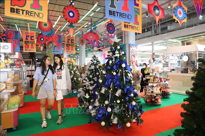 Hai bạn trẻ đi qua những cây thông Noel được trang trí bắt mắt bên trong Chợ Giáng sinh ở TTTM Emsphere. Ảnh: Đỗ Sinh P/v TTXVN tại Bangkok
