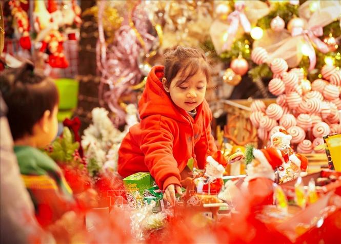 A kid enjoys picking toys on Hang Ma street. VNA Photo: Khánh Hoà